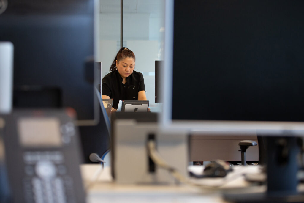 Woman seen inbetween computer screens cleaning and tidying desks