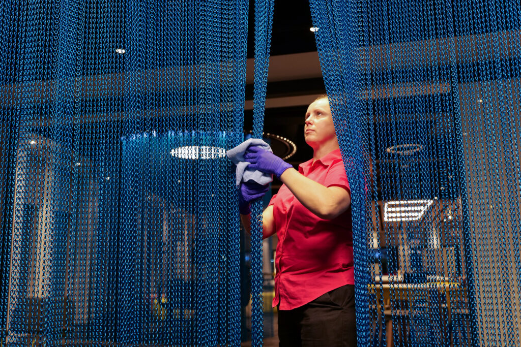 a woman with clothes on cleaning a blue chain curtain with a cloth